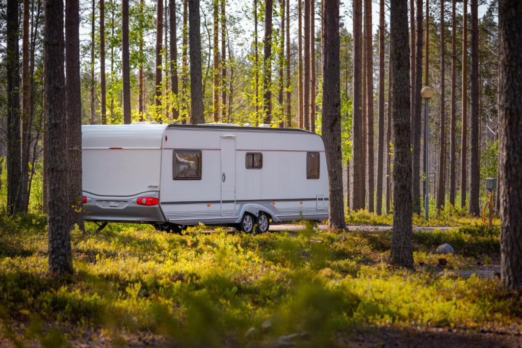 A white camper in a forest of a campground 