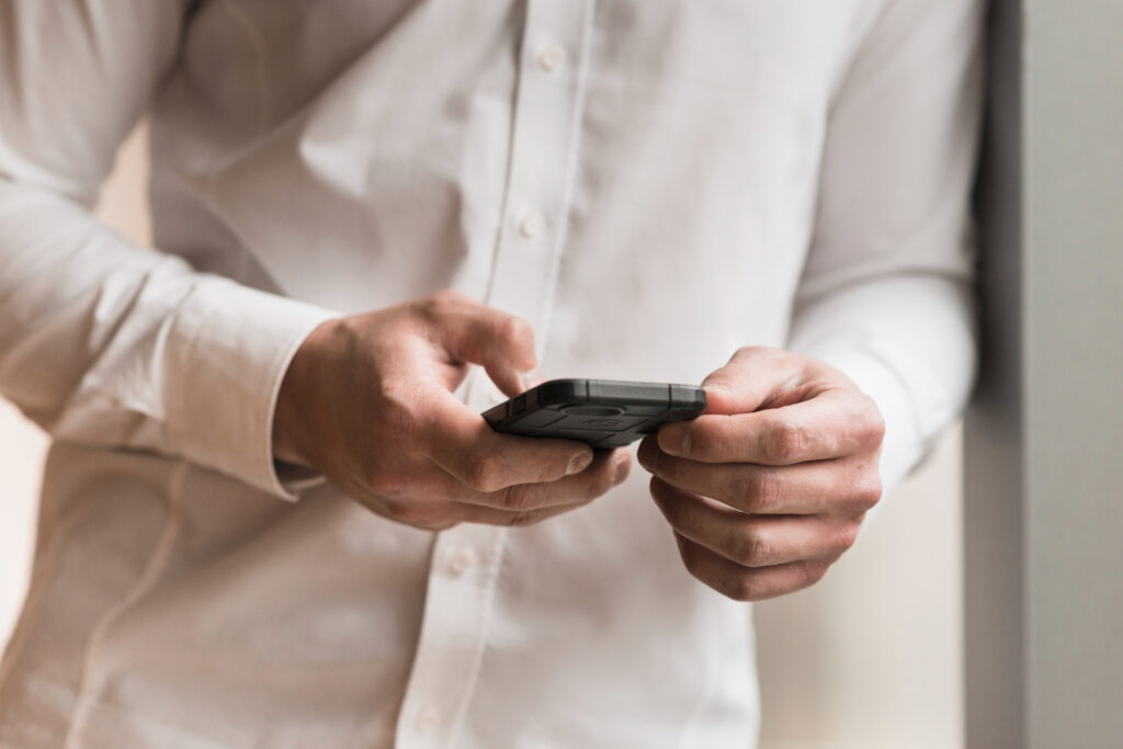 Man in a white shirt using his phone to process payment with a campground software 