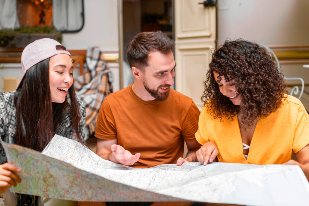 A group of friends with yellow, orange and green t-shirt watching a map in a campground