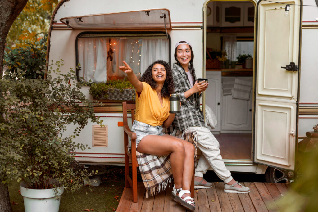 two happy womens enjoying a day in nature in a white camper surrounded by plants and trees