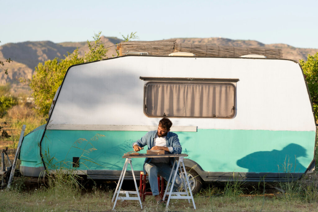 Man enjoying his day in his white and blue camper in the mountains using rv park reservation software