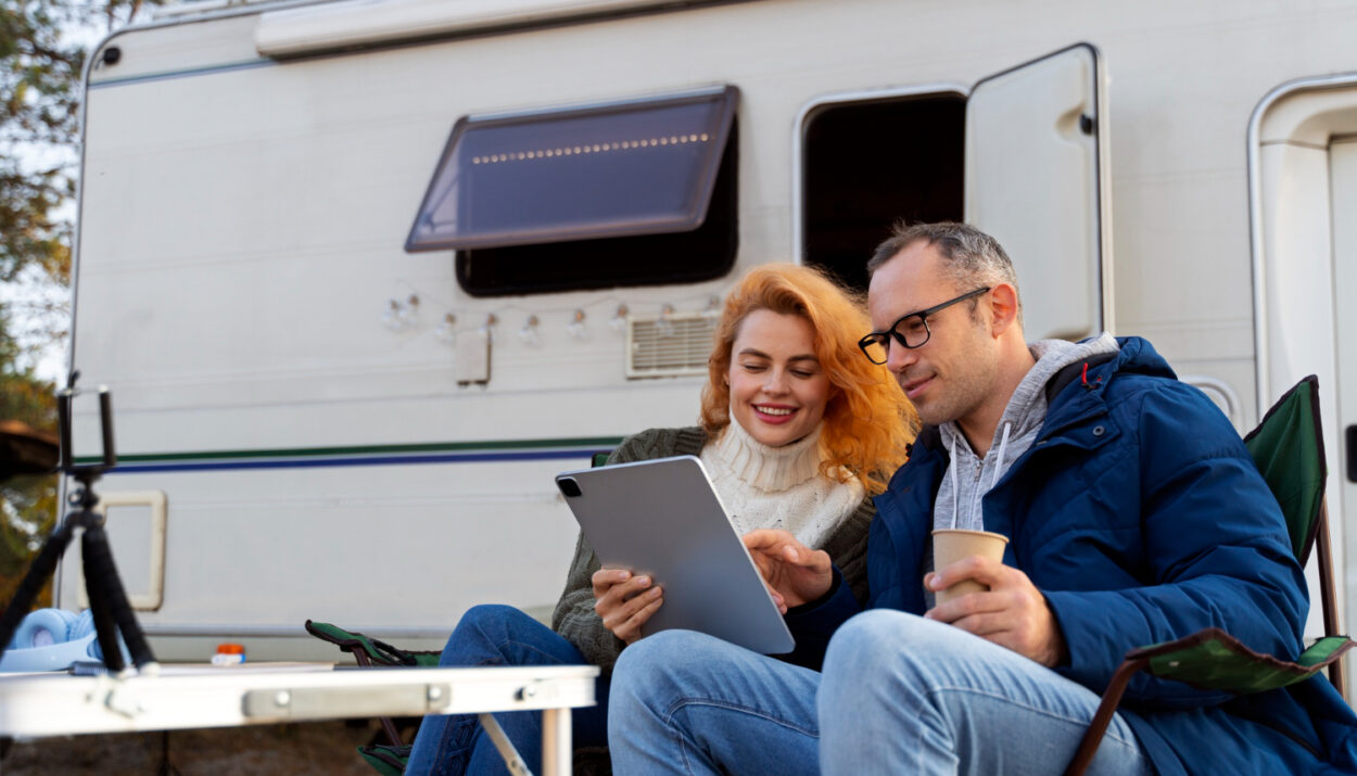 two people using a campground reservation software in front of a white camper