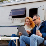 two people using a campground reservation software in front of a white camper