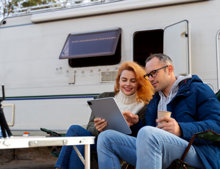 two people using a campground reservation software in front of a white camper