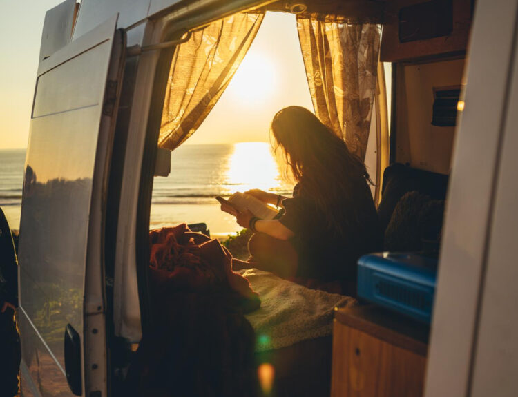 Woman enjoying a beautiful view inside of a camper in front of the beach