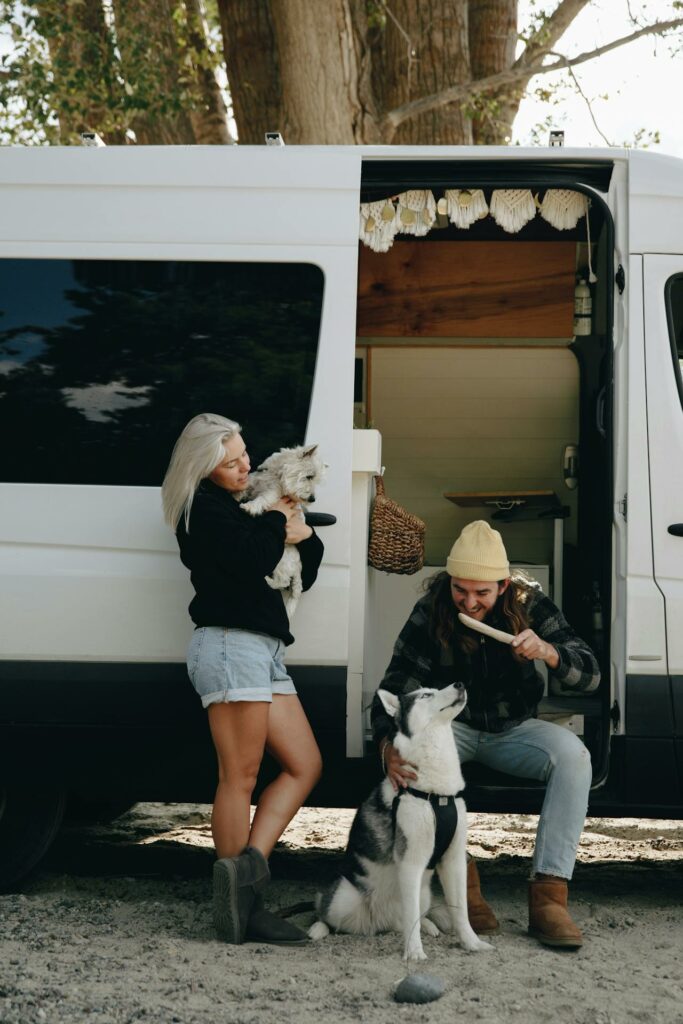 Couple with huskys in a black and white camper