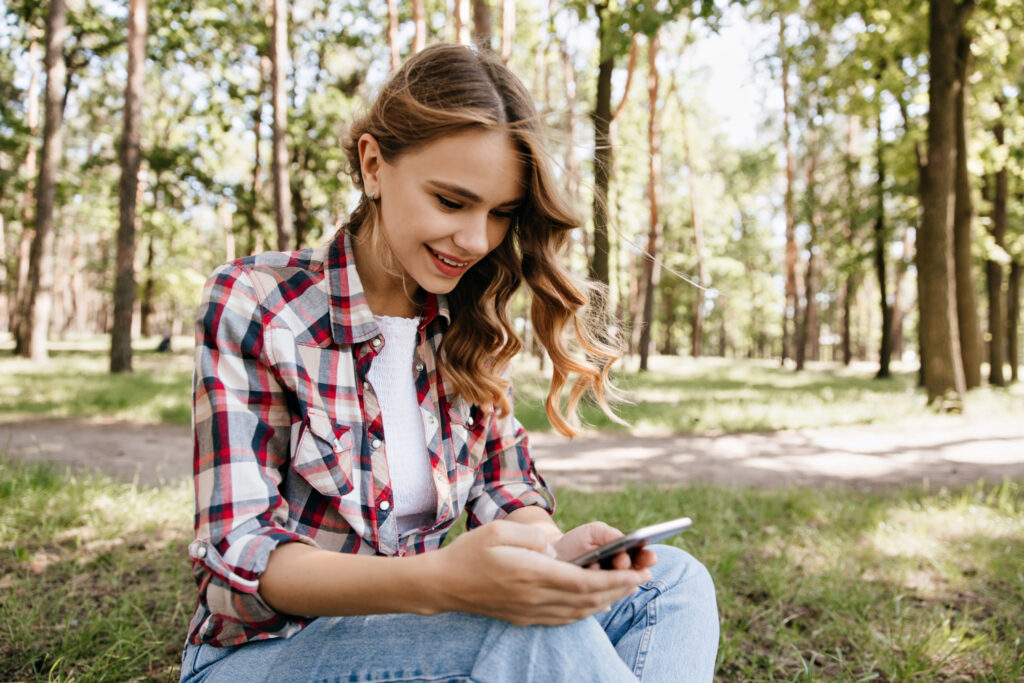 A woman in a plaid blouse using her phone to check the availability of a campground 