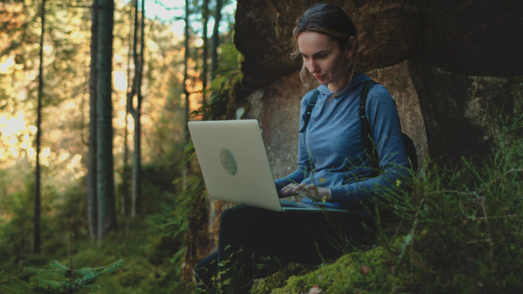 A woman in a blue sueter using her laptop to create a marketing strategy for RV park 