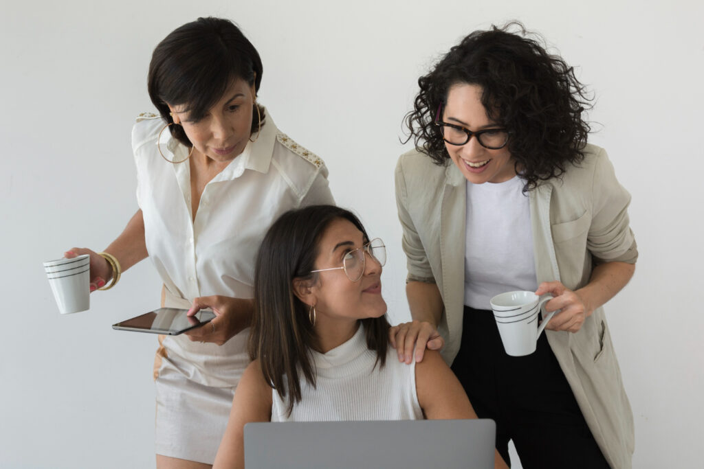 A group of women wearing white and grey clothes learning how to use a management software