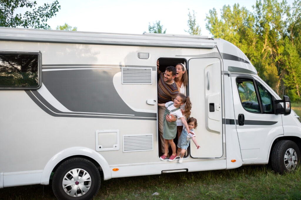 A family of four enjoying a day in a white and grey camper in nature