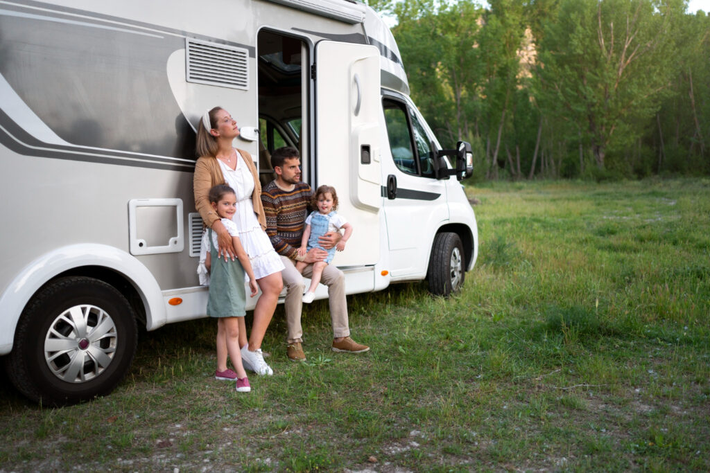 A married couple and their two children outside of a camper van enjoying nature 