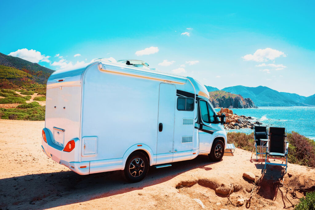 a white camper van in front of a beach of a RV park