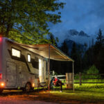 A white camper van with people enjoying a night in nature