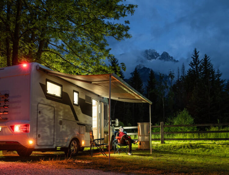 A white camper van with people enjoying a night in nature