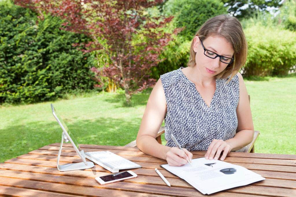 Woman in a blue shirt an Ipad and her phone calculating prices of her campground