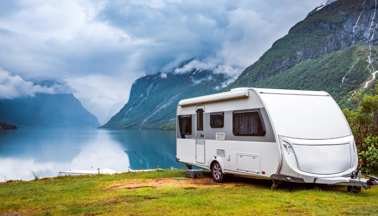 A white camper van in front of a lake with mountains