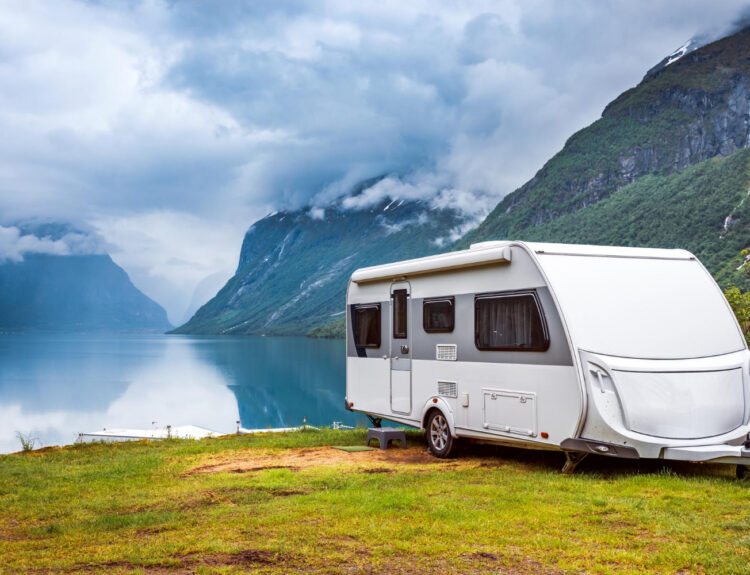 A white camper van in front of a lake with mountains