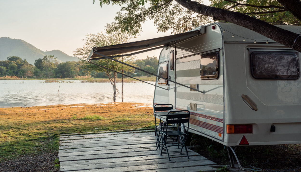 A white and brown camper in front of a lake