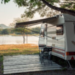 A white and brown camper in front of a lake