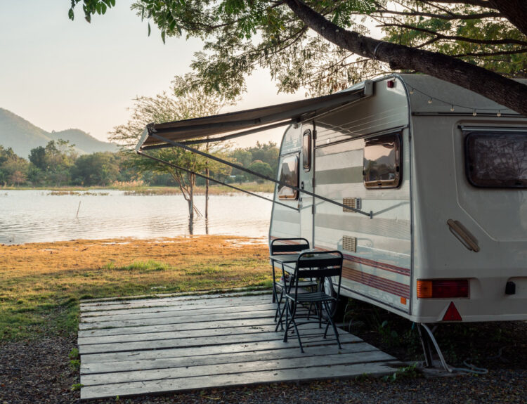 A white and brown camper in front of a lake