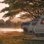 A group of campers in a campground in front of a lake at sunset