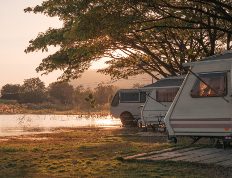 A group of campers in a campground in front of a lake at sunset