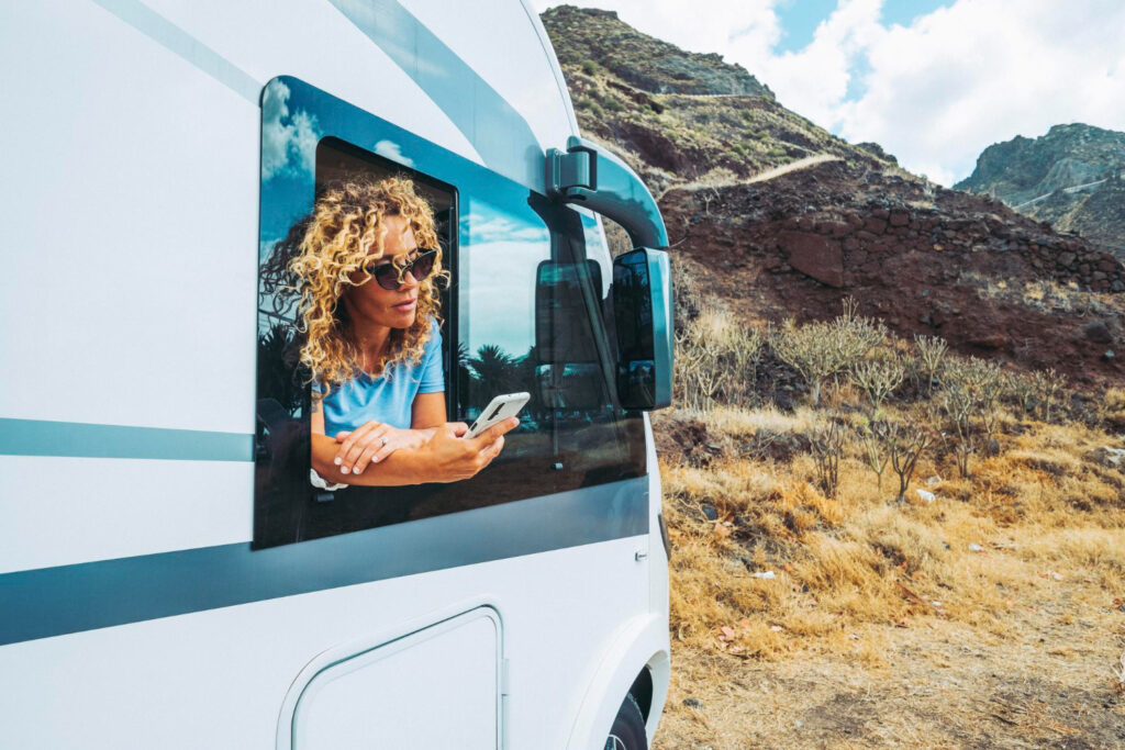 A woman inside of a camper van checking her phone to see her next campground reservation