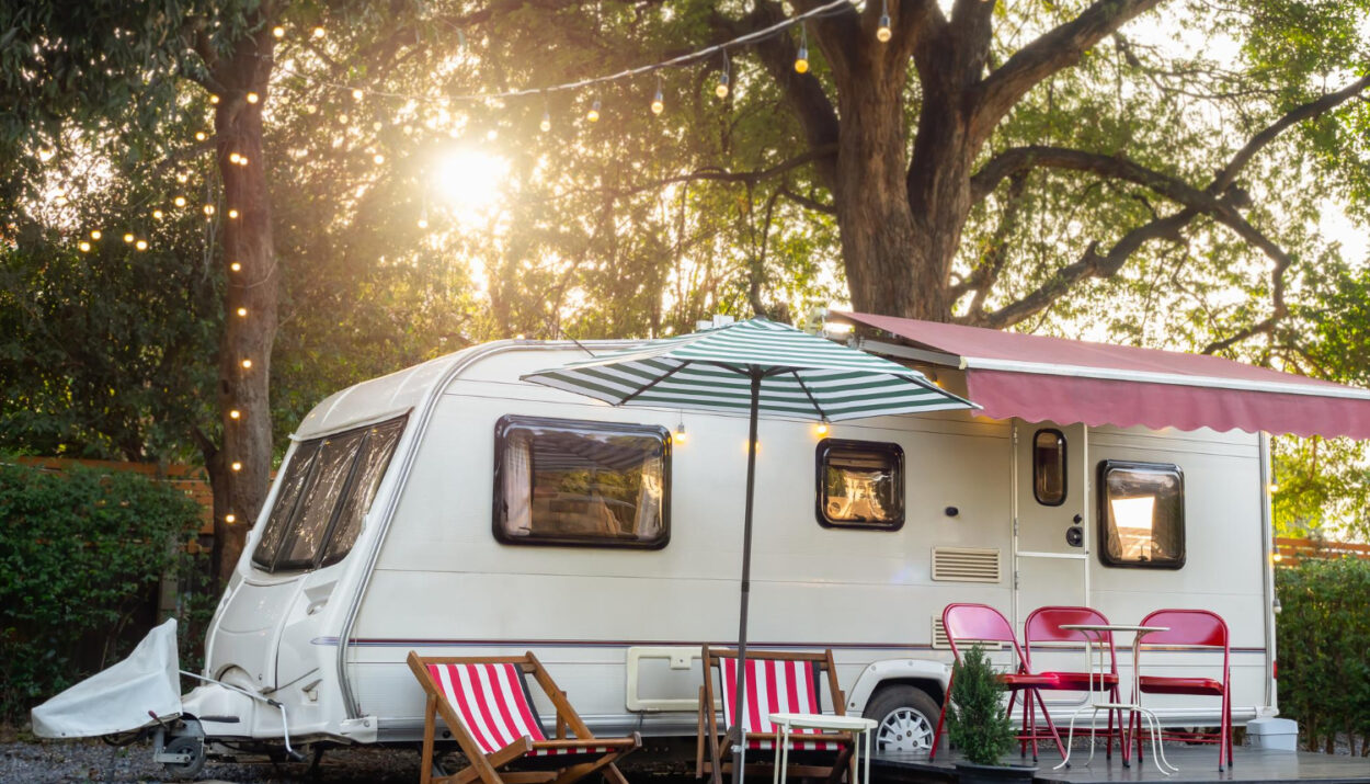 a white camper van in the forest with a beautiful sunset behing and red chairs