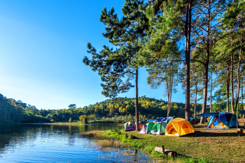 a group of campings in front of a lake enjoying a day in nature 