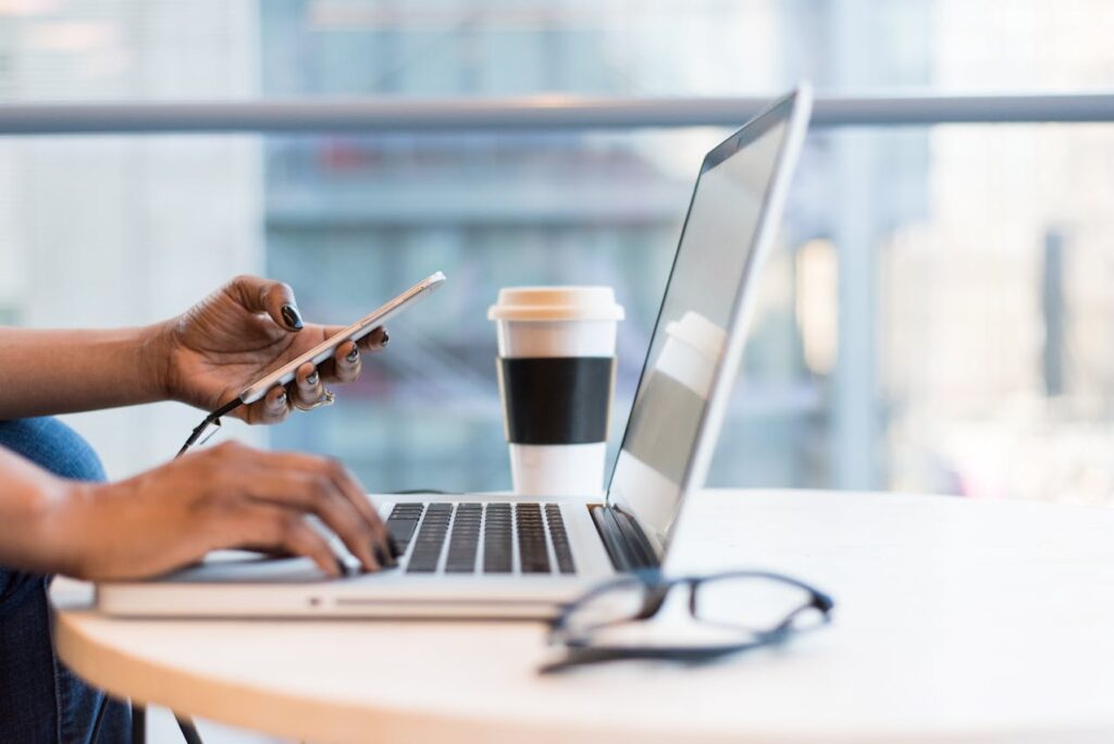 Person using a laptop with a white and black coffee cup