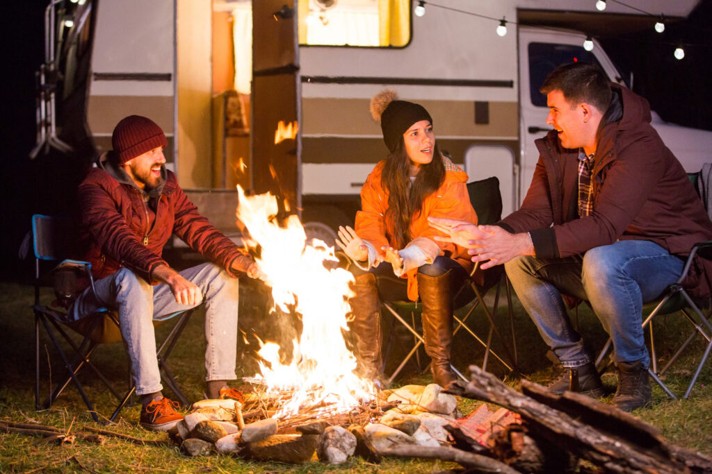 a group of people enjoying a bonfire outside of their camper van