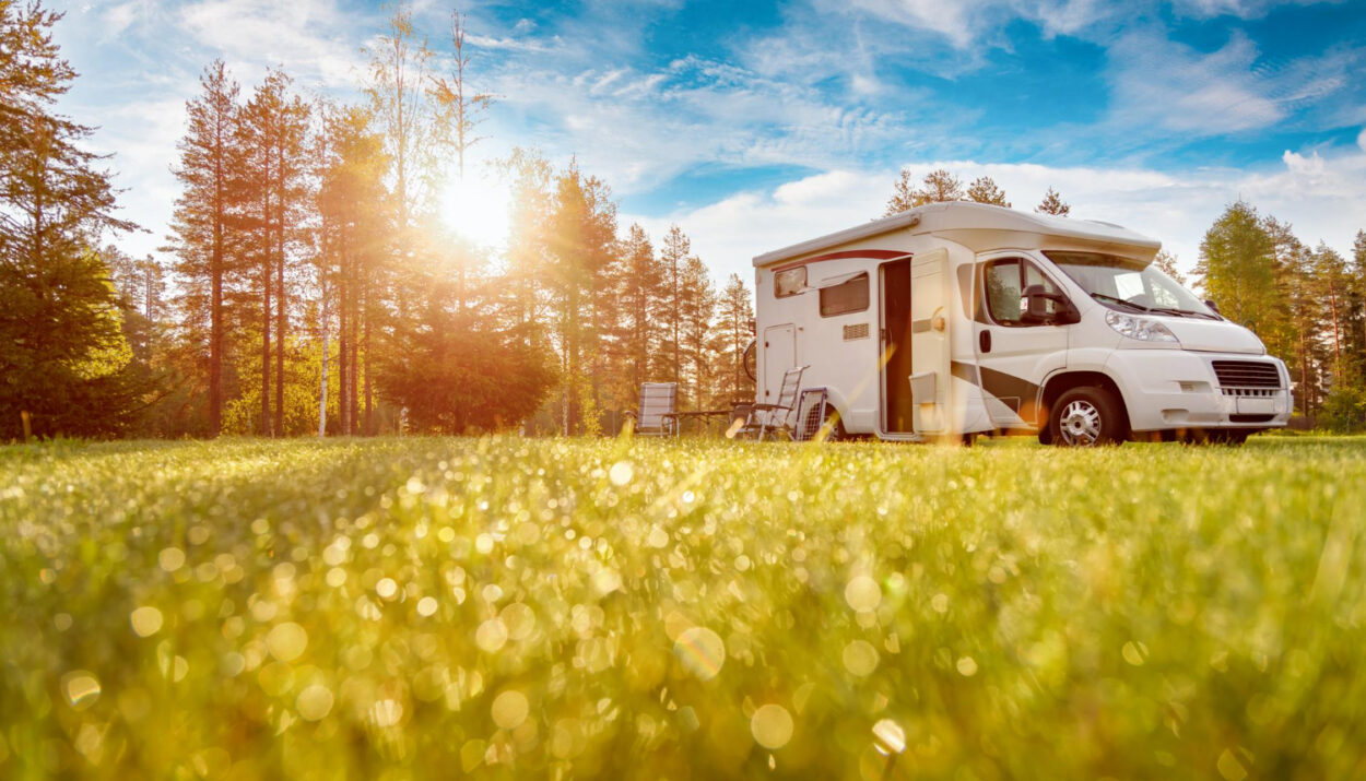 a low POV of a camper van with the grass and a blue sky