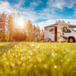 a low POV of a camper van with the grass and a blue sky