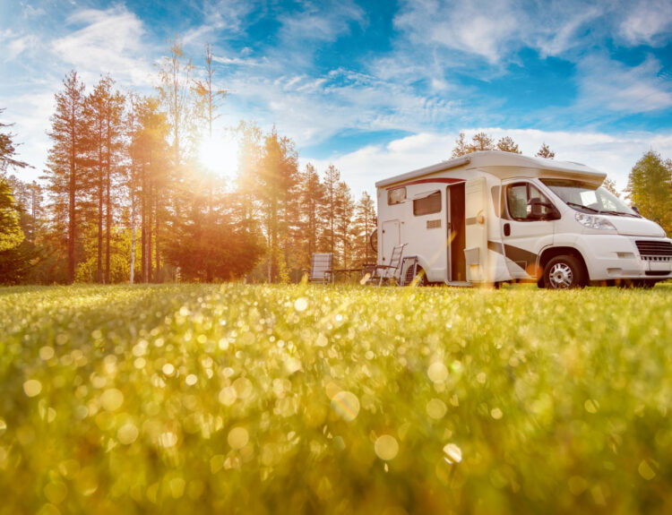 a low POV of a camper van with the grass and a blue sky