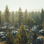 drone view of a campground with a lot of camper vans in the forest