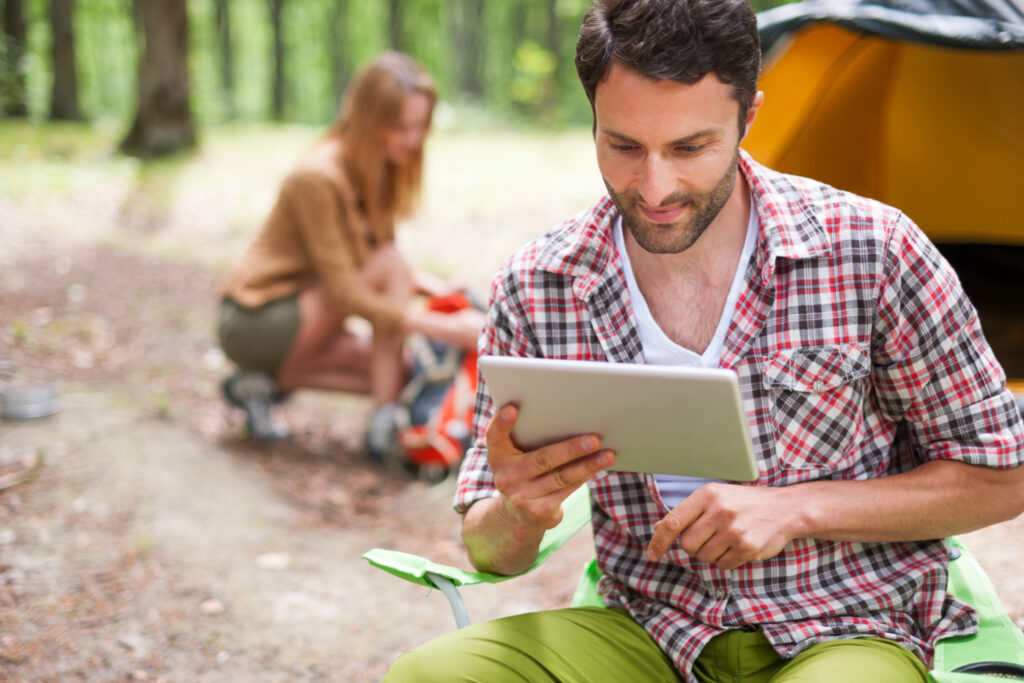 a man in a square shirt using a tablet to check on his campground reservation using RoverPass management software