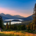 a panoramic view of a camping in the forest on a mountain with the sunet to the left