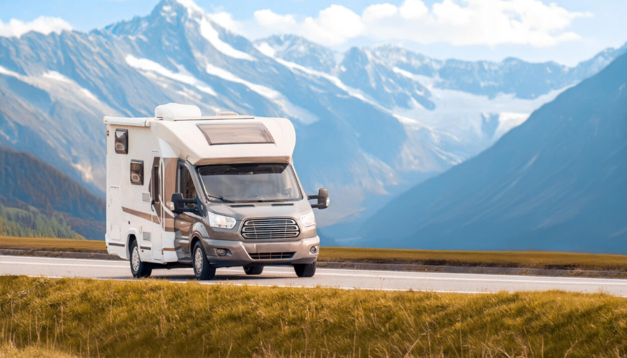 A camper van on the road with muntains behind it