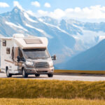 A camper van on the road with muntains behind it