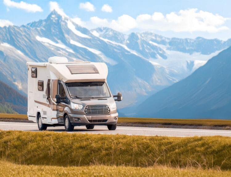 A camper van on the road with muntains behind it