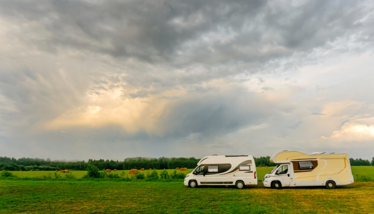 Two camper vans on the road with a cloudy sky