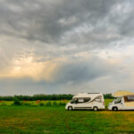 Two camper vans on the road with a cloudy sky