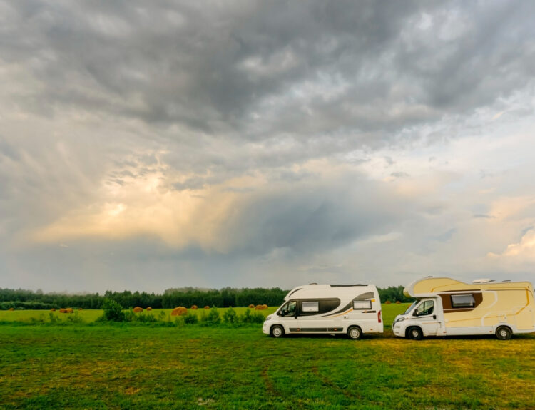 Two camper vans on the road with a cloudy sky