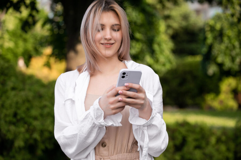 A woman in a white shirt using her phone to make a reservation using campground booking software 