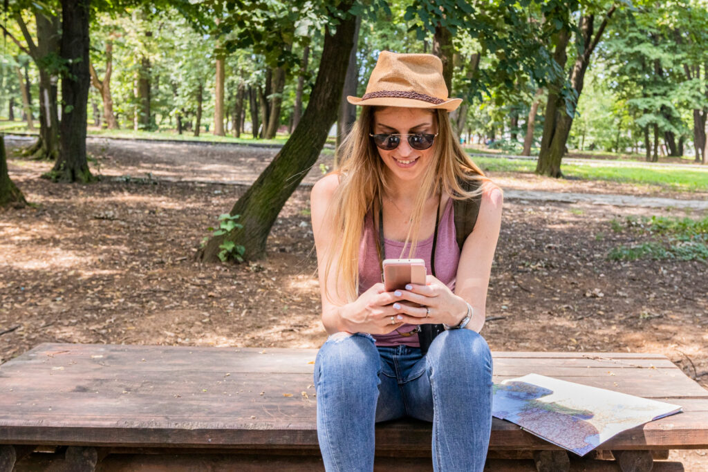 a woman in a pink top and blue jeans sitting in a wodden bench giving a positive feedback of a RV park using campsite management software 