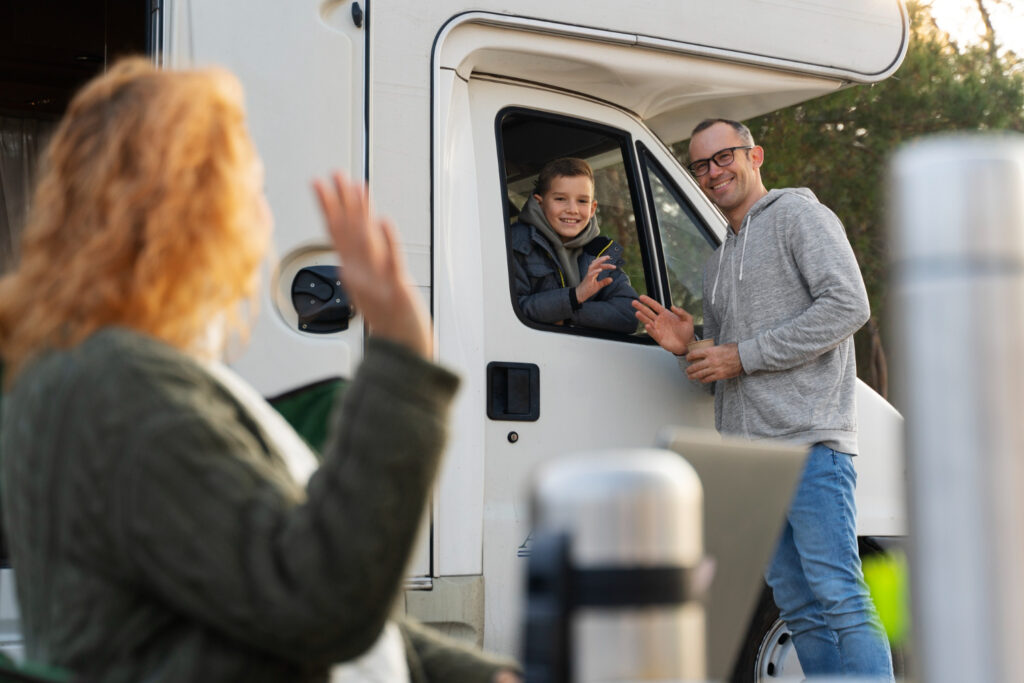 a family waving at each other enjoying their stay at a RV park thanks to campsite reservation software