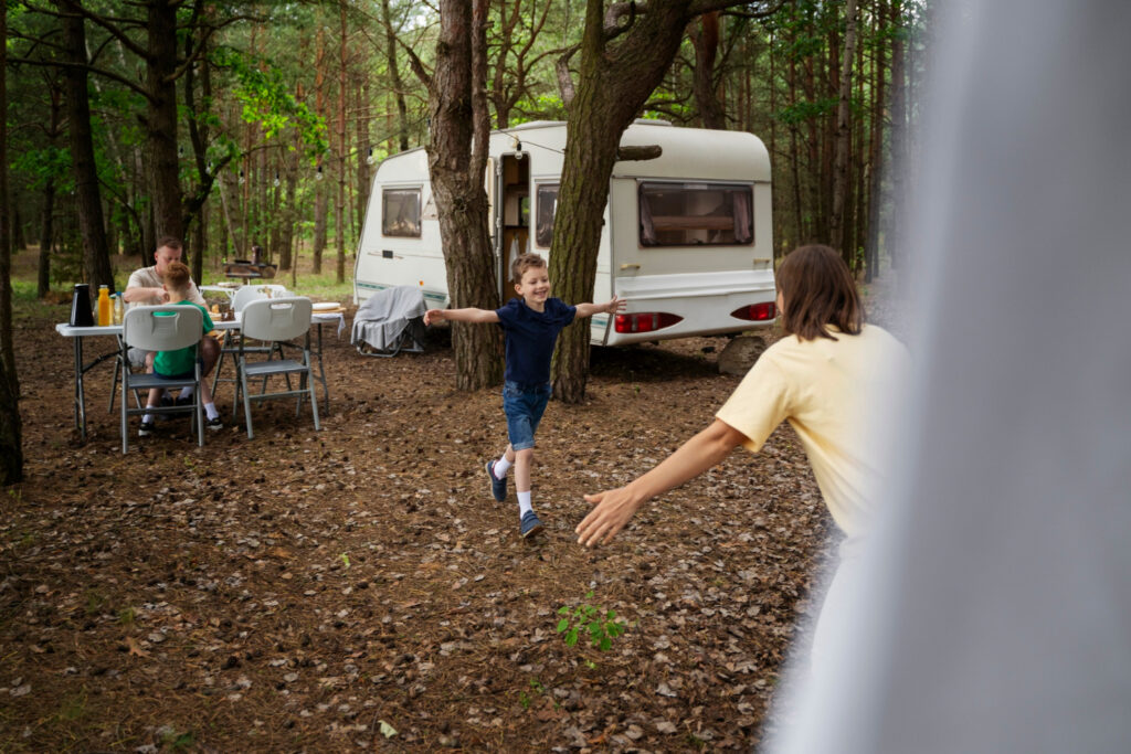 A kid running towards his mother outside of a camper van in the forest 