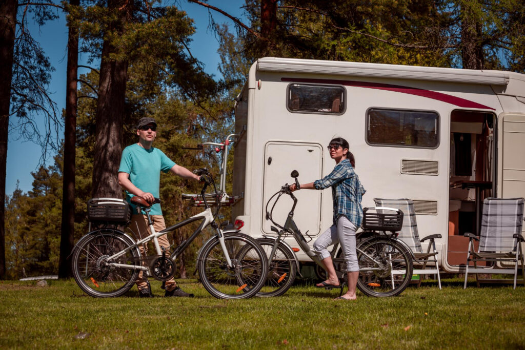 Two people with their bikes outside of their camper van in a RV park