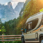 A grey camper van staying in front of a mountain