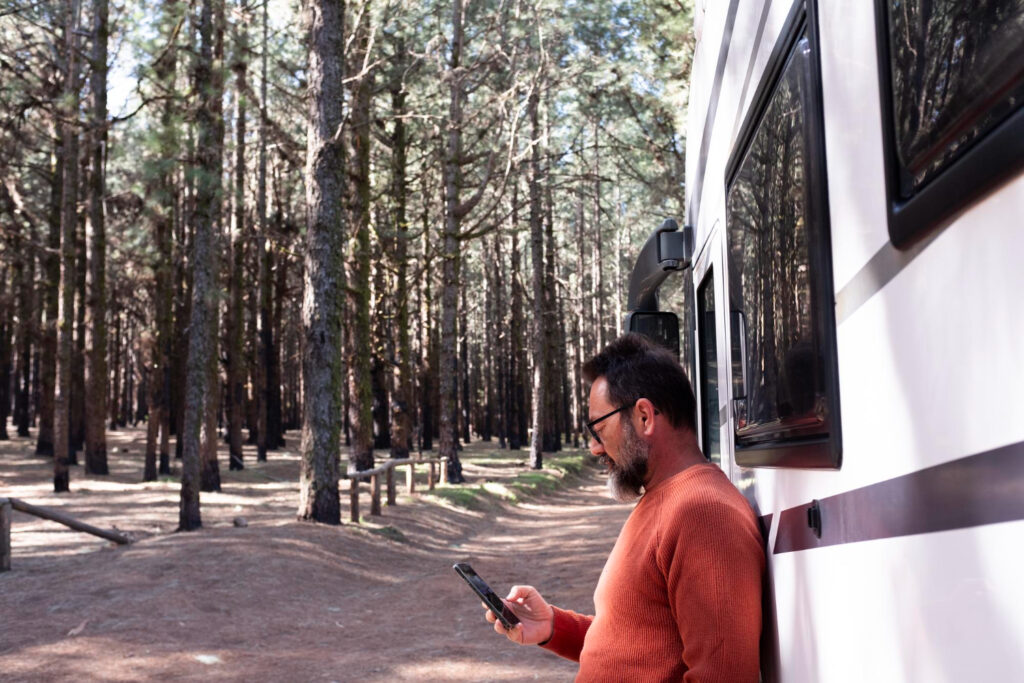 a man with an orange sueter using his phone making a reservation using campground booking software